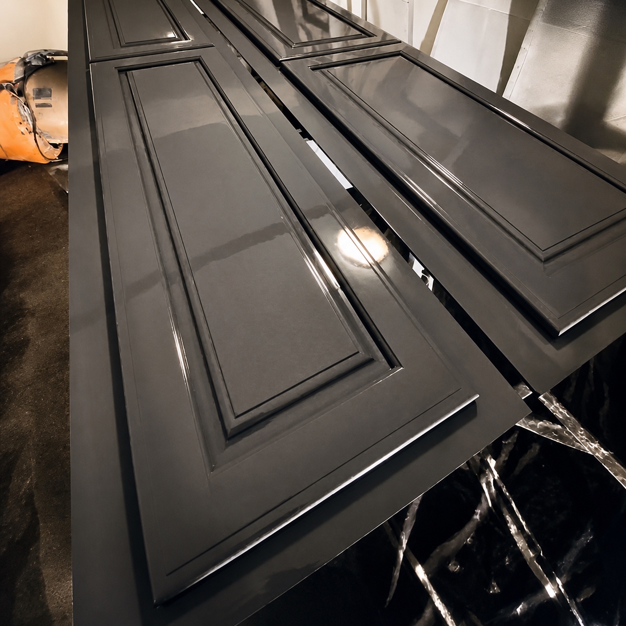 Cabinet doors laid out in the spray booth with a smooth grey sprayed finish, by Genesis Pro Painting in Westchester NY