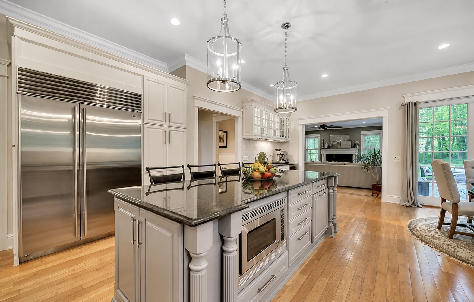 Refinished white kitchen cabinets with a grey island and panelled refrigerator surround by Genesis Pro Painting