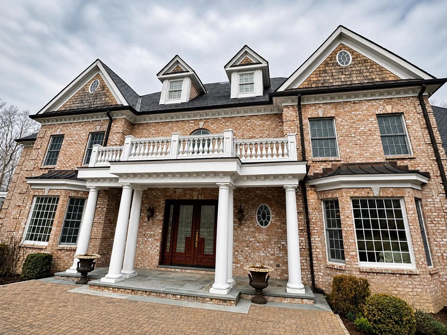 Brick colonial with white columns, balustrade, dormers and cedar shingle gables, trim and portico painted white, by Genesis Pro Painting in Westchester NY