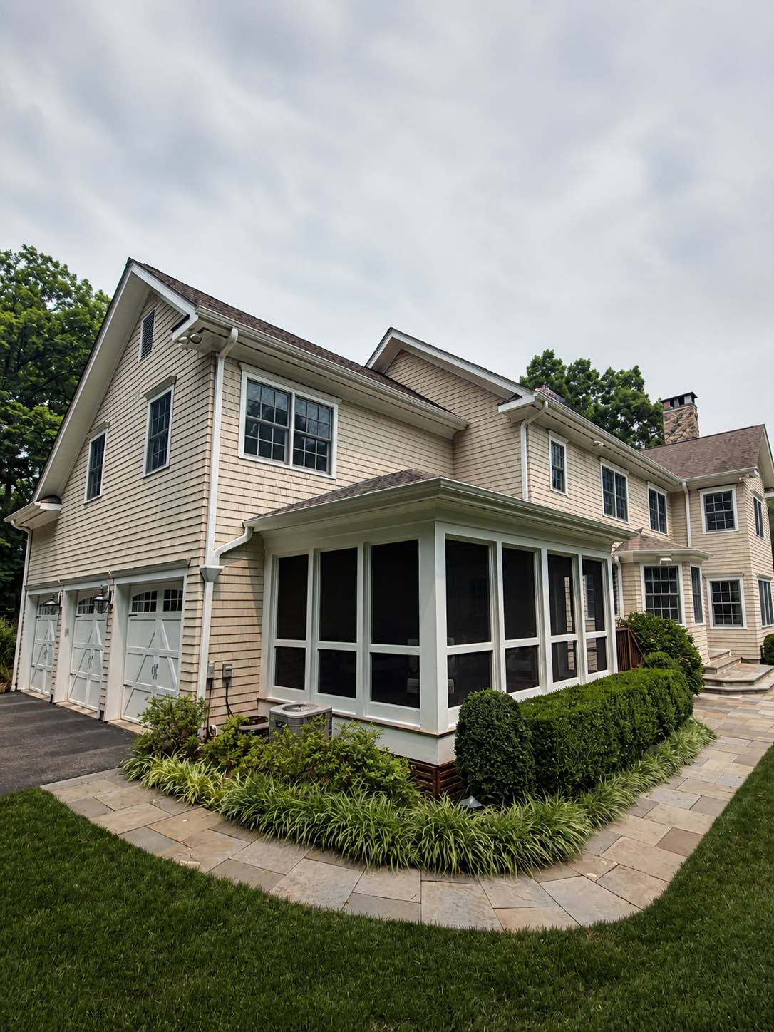 Exterior painted screened porch with white trim, cedar shingle siding, and garage doors by Genesis Pro Painting