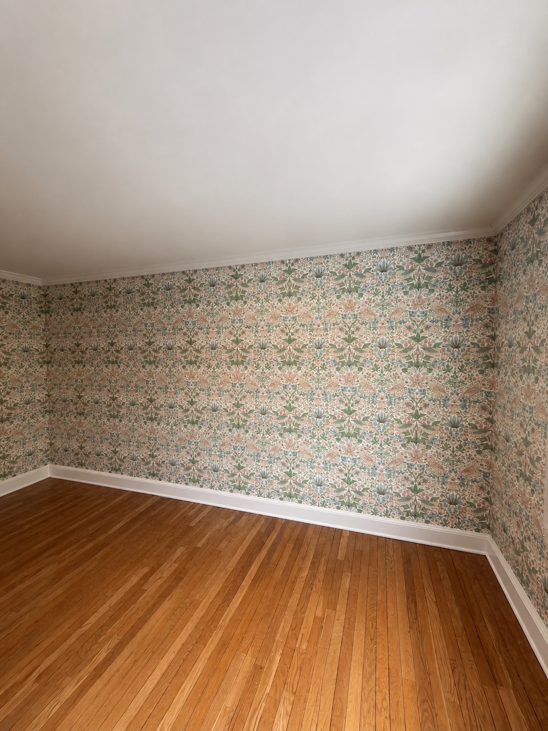 Morris style floral wallpaper installed to the crown molding with the repeat aligned across the corner by Genesis Pro Painting