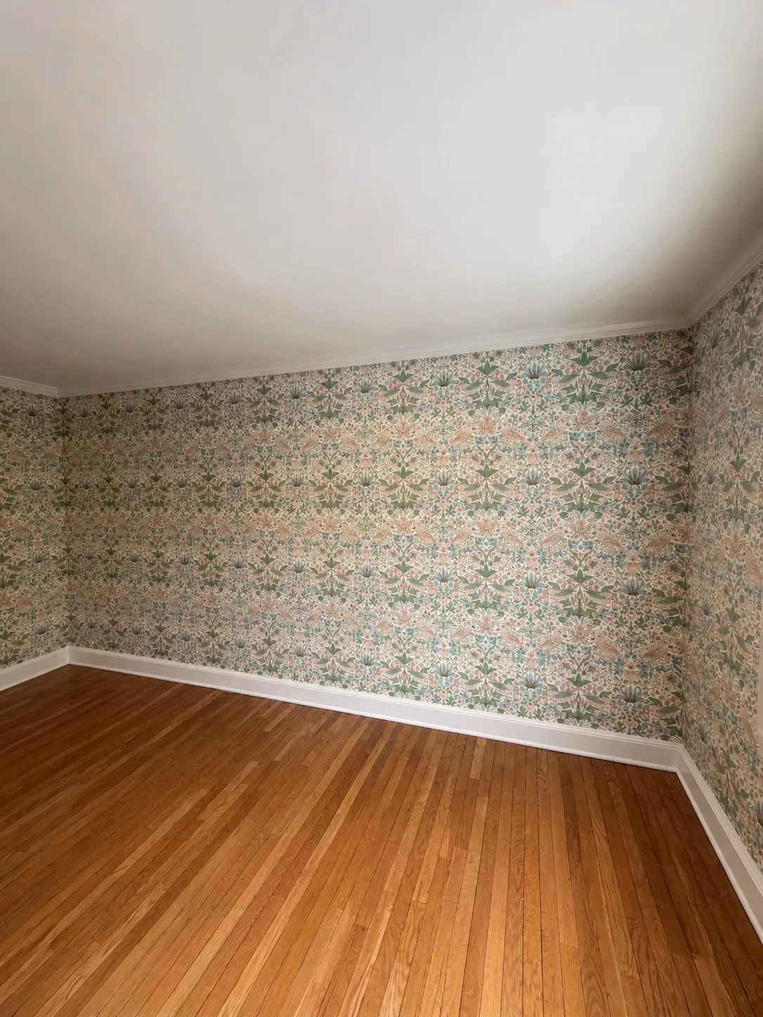 Morris style floral wallpaper installed to the crown molding with the repeat aligned across the corner by Genesis Pro Painting
