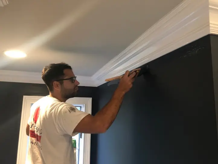 Genesis Pro Painting worker brushing a precise edge along white crown molding