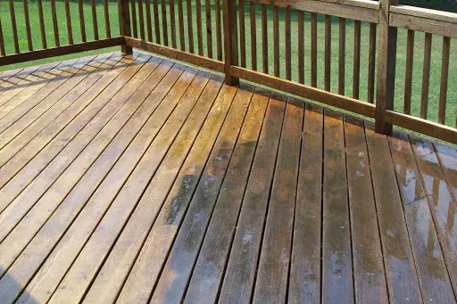 Wet wood deck boards and railing during cleaning before refinishing