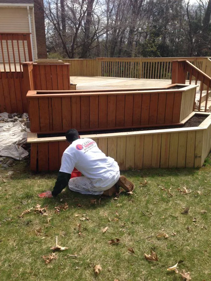 Painter applying stain to the outside of a wood deck