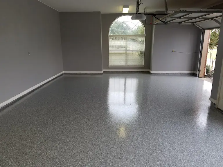 Garage with gray painted walls, white baseboards and a finished epoxy floor