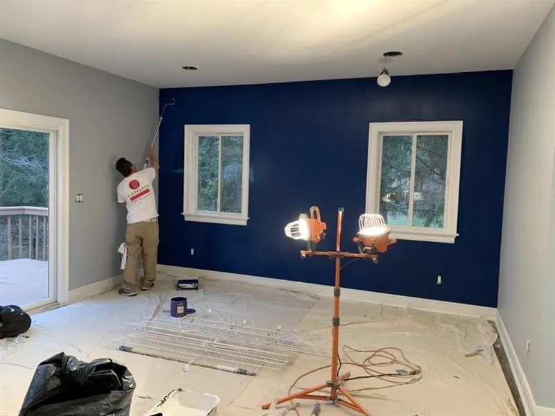 Deep blue accent wall with white window trim during an interior repaint