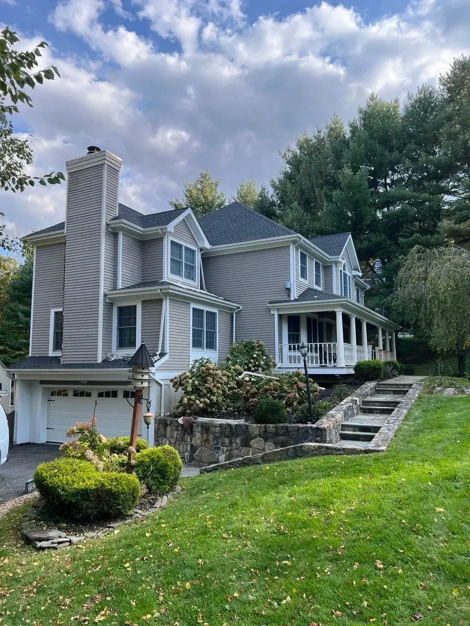 Finished exterior painting project in Bedford NY, a two-story colonial with gray siding, white trim, covered porch and attached garage