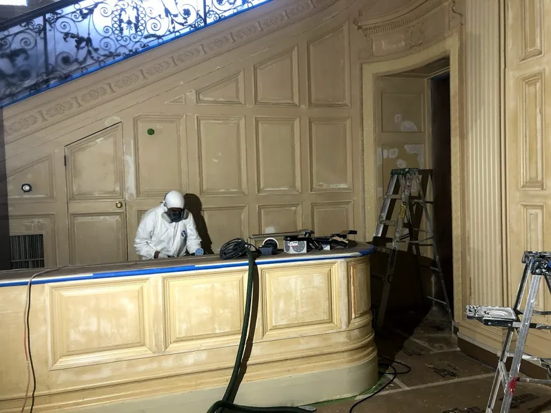 Worker preparing decorative wood paneling with dust extraction equipment and protected flooring